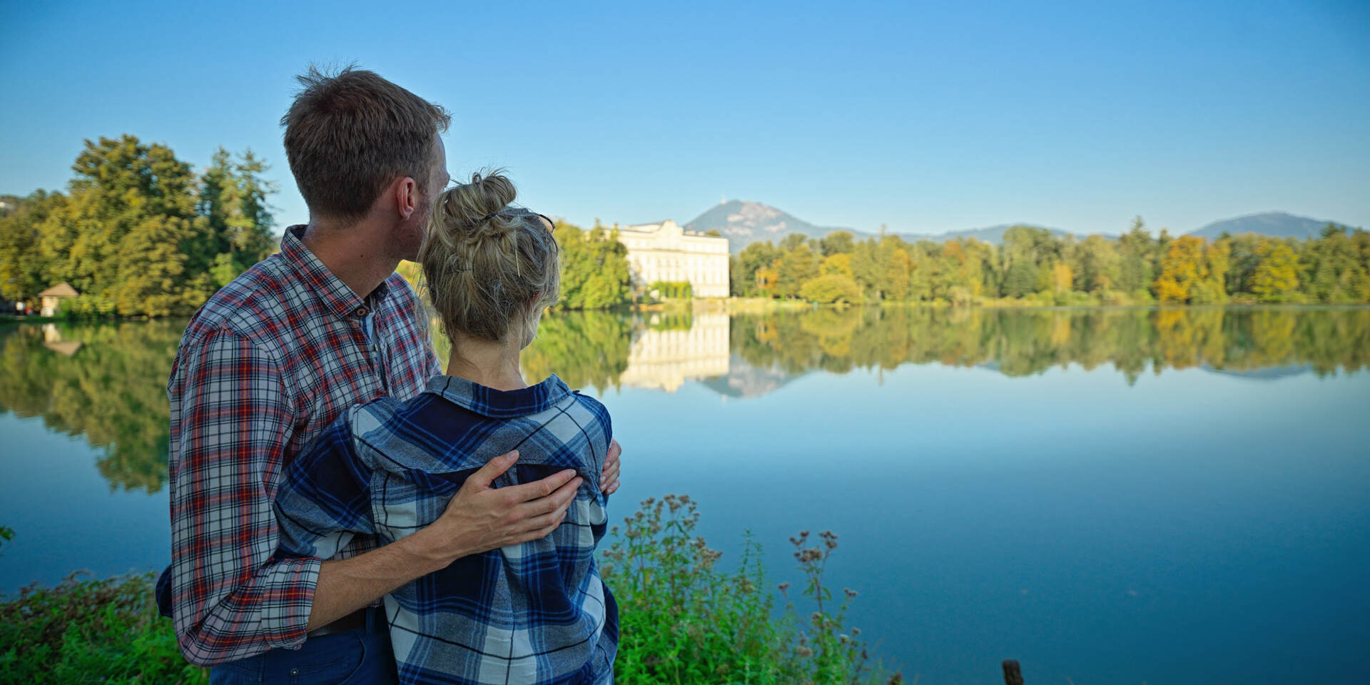 Paar umarmt sich vor dem Leopoldskroner Weiher beim Schloss Leopoldskron auf der Sound of Music Tour von Salzburg Panorama Tours