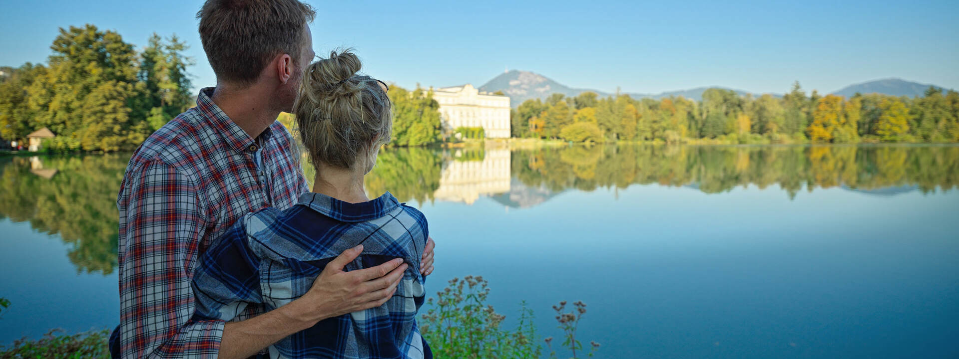 Paar umarmt sich vor dem Leopoldskroner Weiher beim Schloss Leopoldskron auf der Sound of Music Tour von Salzburg Panorama Tours