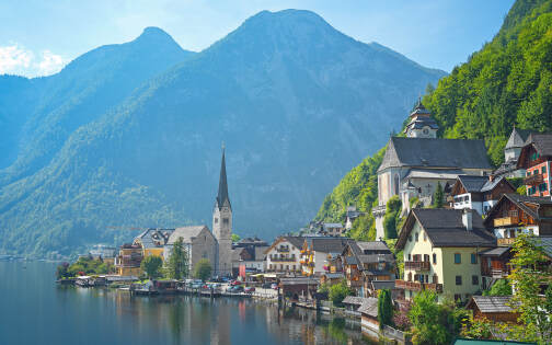 Hallstatt - Blick auf den Ort mit der Kirche, daneben der Hallstätter See und die Berge - Hallstatt Tour mit Salzburg Panorama Tours